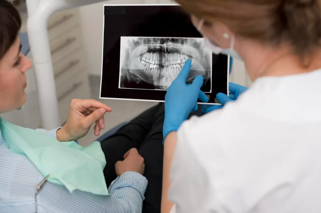 Dentist showing dental X-ray to patient, assessing if impacted wisdom teeth are causing facial pain or headaches.