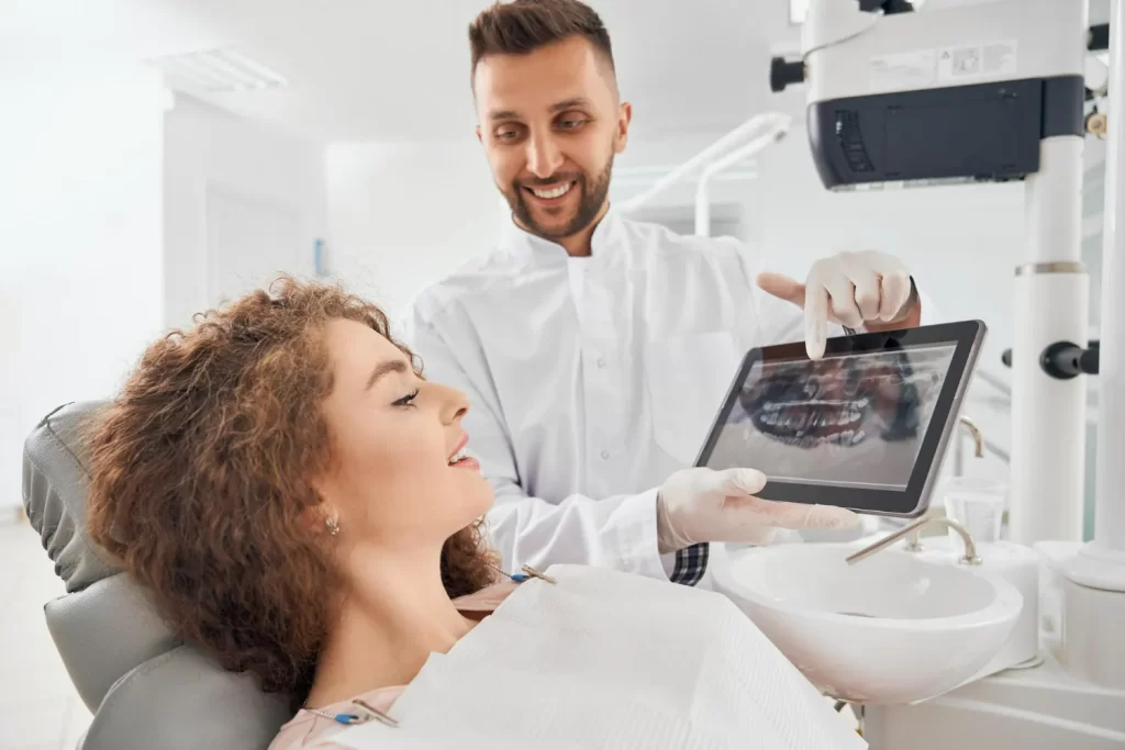 Dentist showing CBCT scan to patient while discussing tooth implant vs dental bridge options.
