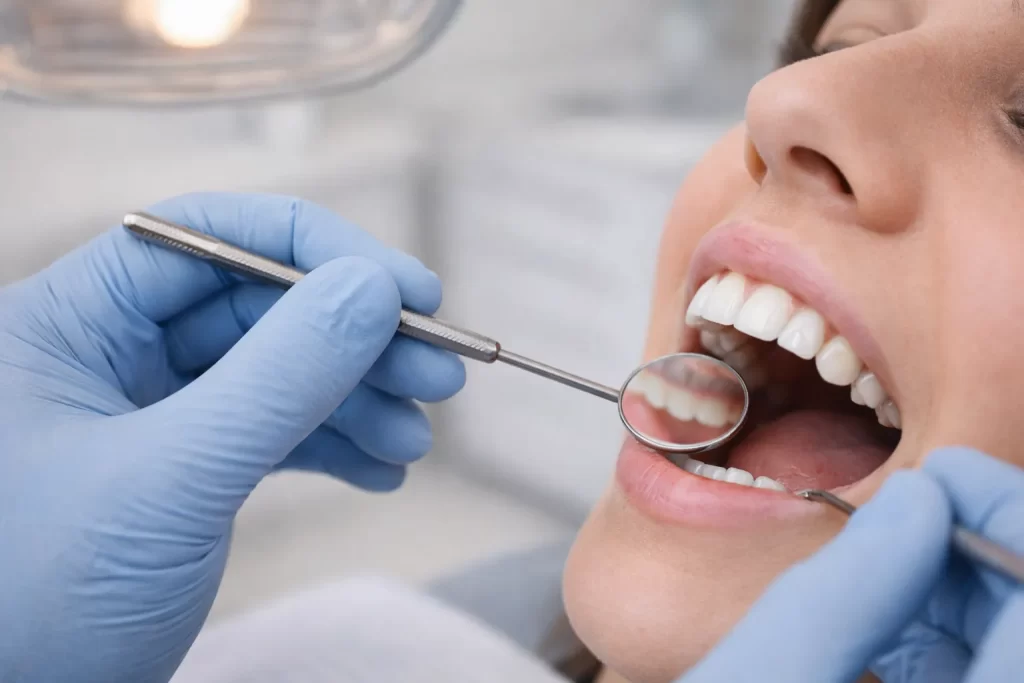 Routine dental examination showing teeth assessed with a mirror under soft lighting in a calm clinical setting.