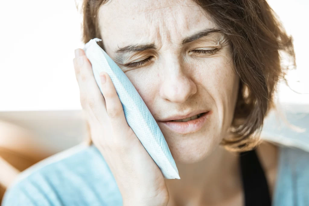 Woman holding a cold compress to her cheek for tooth sensitivity.