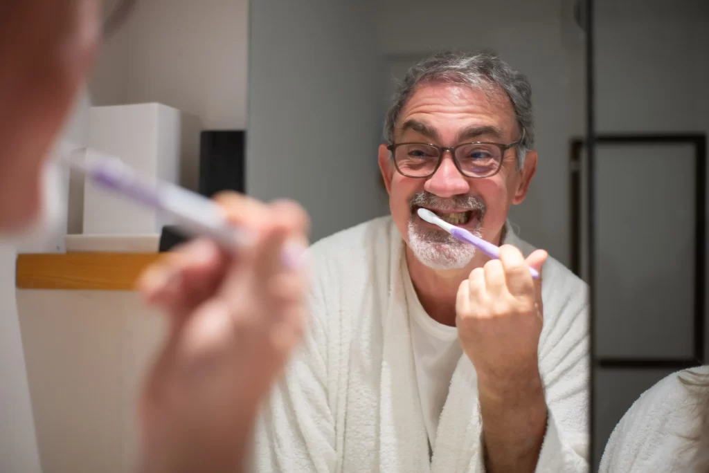 Older man brushing along the gumline as part of his daily oral care routine.